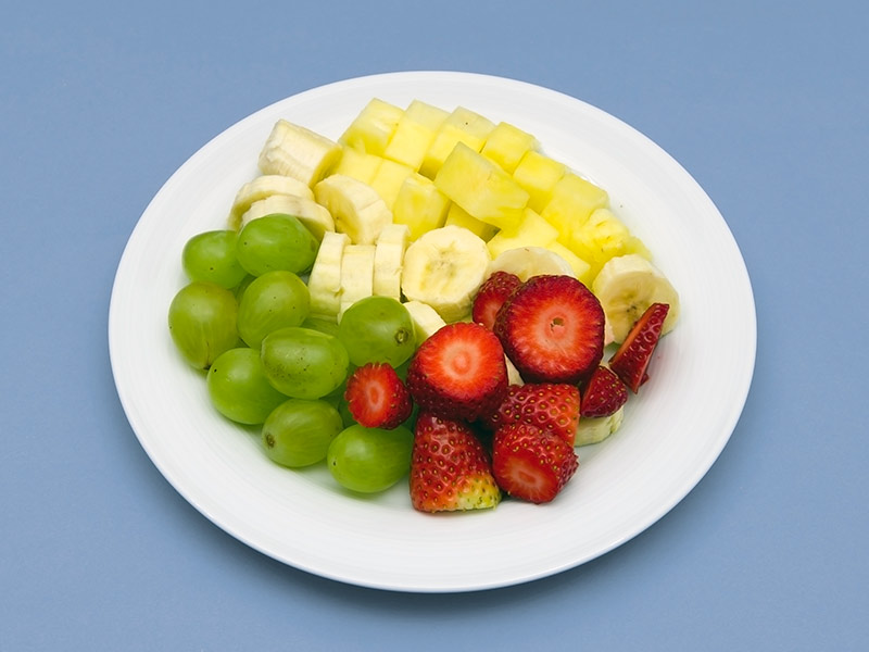 Obstteller: Ananas, Banane, Weintrauben und Erdbeeren